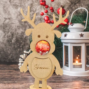 May include: Wooden reindeer cutout with a red Lindor chocolate in its mouth. The reindeer has a name tag that says "Shannon".