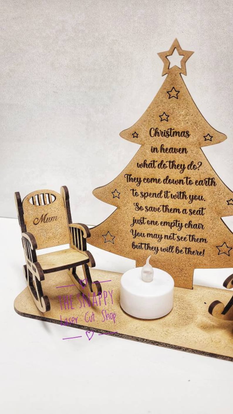 Puede incluir: Adorno de &aacute;rbol de Navidad de madera con una mecedora y una vela encendida. El &aacute;rbol tiene el texto "Navidad en el cielo, &iquest;qu&eacute; hacen? Bajan a la tierra para pasarlo contigo. As&iacute; que res&eacute;rvales un asiento, solo una silla vac&iacute;a. Puede que no los veas, pero estar&aacute;n ah&iacute;!" La mecedora tiene la palabra "Mam&aacute;" en la parte posterior.