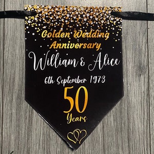 May include: Black and gold banner with a gold glitter background. The banner reads "Golden Wedding Anniversary William & Alice 6th September 1973 50 Years" with two gold hearts at the bottom.