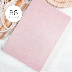Könnte beinhalten: Ein hellrosa B6-Papier mit einem 3,7-mm-Raster. Das Papier hat eine strukturierte Oberfläche und ist leicht angewinkelt. Der Text "B6 (3.7mm grid)" befindet sich in einem weißen Kreis. Das Papier liegt auf einer weißen Oberfläche.