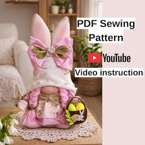 Può includere: Una bambola gnomo pasquale fatta a mano con capelli intrecciati rosa, un cappello bianco e un fiocco rosa. Lo gnomo tiene in mano un cestino con uova di Pasqua. L'immagine include il testo "PDF Sewing Pattern" e "YouTube Video instruction".