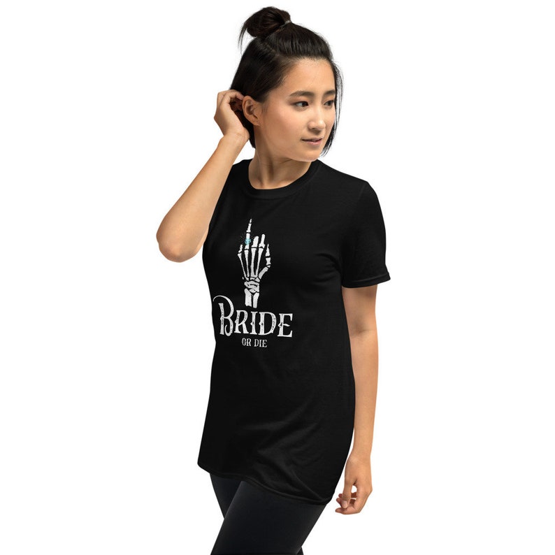 May include: Black t-shirt with a white skeleton hand wearing a ring and the text "Bride or Die" printed on the front.