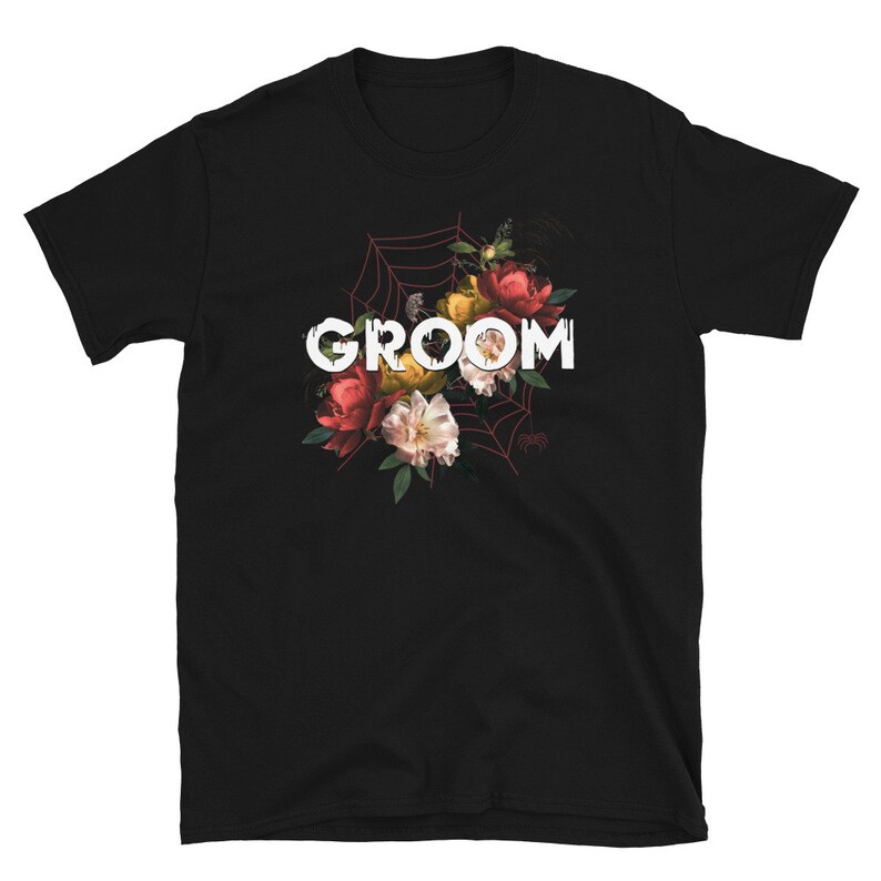 May include: Black t-shirt with a floral design and the word "GROOM" in white letters.