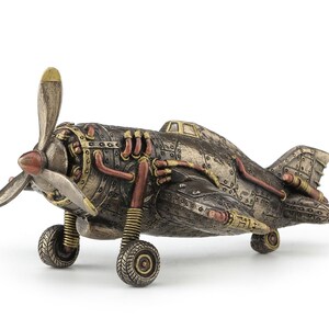 May include: A steampunk-style airplane figurine made of metal with a brown, gold, and copper finish. The airplane has a propeller, wings, and a detailed engine.
