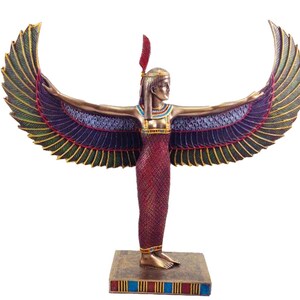 May include: A gold and red statue of the Egyptian goddess Isis with outstretched wings. The statue is standing on a base with blue and gold accents.