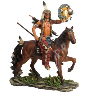 Puede incluir: Una figurita pintada a mano de un guerrero nativo americano montando un caballo marrón. El guerrero lleva un tocado de plumas y sostiene una lanza. El caballo tiene marcas blancas y se levanta sobre sus patas traseras.