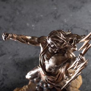 K&ouml;nnte beinhalten: Eine Bronzestatue eines griechischen Gottes, der einen Blitz h&auml;lt. Die Statue ist detailliert und realistisch, mit einem muskul&ouml;sen K&ouml;rperbau und wallendem Haar. Der Gott ist in einer dramatischen Pose dargestellt, mit erhobenem Arm und hoch gehaltenem Blitz.