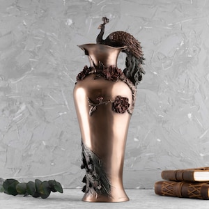 Puede incluir: Un jarr&oacute;n de cobre decorativo con un dise&ntilde;o de pavo real. El jarr&oacute;n tiene un patr&oacute;n floral y es una hermosa pieza de decoraci&oacute;n del hogar.