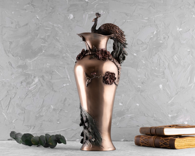Puede incluir: Un jarr&oacute;n de cobre decorativo con un dise&ntilde;o de pavo real. El jarr&oacute;n tiene un patr&oacute;n floral y es una hermosa pieza de decoraci&oacute;n del hogar.