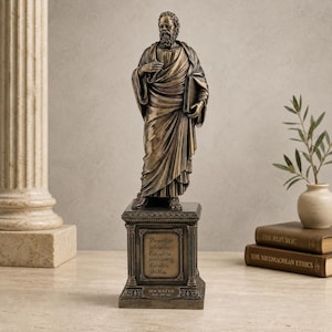 Könnte beinhalten: Eine bronzefarbene Statue von Sokrates auf einem rechteckigen Sockel. Die Figur trägt drapierte Gewänder und hält ein Buch. Der Sockel ist mit Säulen und der Inschrift versehen: The end of life is to be like God, and the soul following God will be like Him. Socrates 469-399 BC.