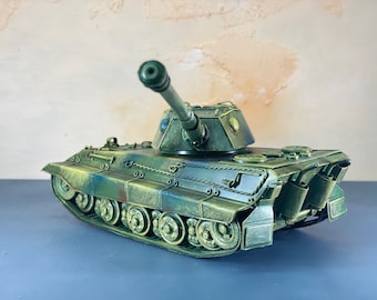 May include: A green and brown model tank with a long barrel and a detailed design. The tank is on a gray surface.