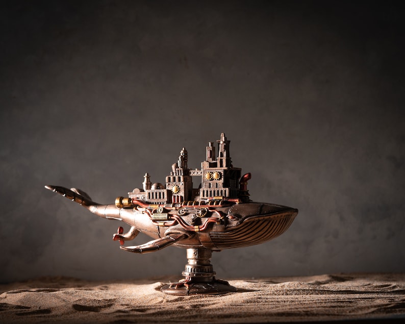 Op de afbeelding: Een steampunk-walvisbeeld met ingewikkelde details en een metalen afwerking. De walvis staat op een standaard en heeft een stadachtige structuur op zijn rug.