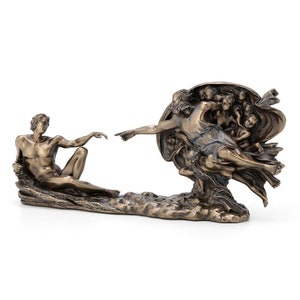 May include: A bronze-toned sculpture depicting the Creation of Adam, featuring two figures reaching toward each other with extended fingers. The piece shows a reclining figure on the left and a group of figures on the right, all finished in a metallic bronze color with dark highlights to emphasize the detailed musculature and flowing drapery.