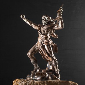 K&ouml;nnte beinhalten: Eine Bronzestatue von Zeus, dem griechischen Gott des Himmels und des Donners, der einen Blitz in seiner rechten Hand h&auml;lt. Die Statue steht auf einem felsigen Sockel mit der Inschrift "ZEUS".