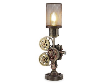 May include: A steampunk-style table lamp with a metal lampshade and a projector-shaped base with gears. The lamp is lit with a warm white light bulb.