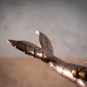 Op de afbeelding: Een metalen staartvin in steampunk-stijl met ingewikkelde details en een koperen afwerking.