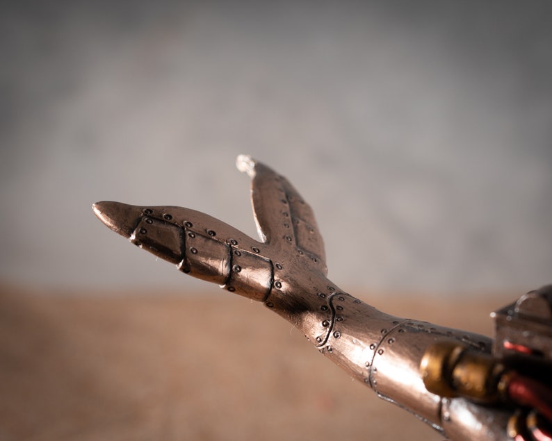 Op de afbeelding: Een metalen staartvin in steampunk-stijl met ingewikkelde details en een koperen afwerking.