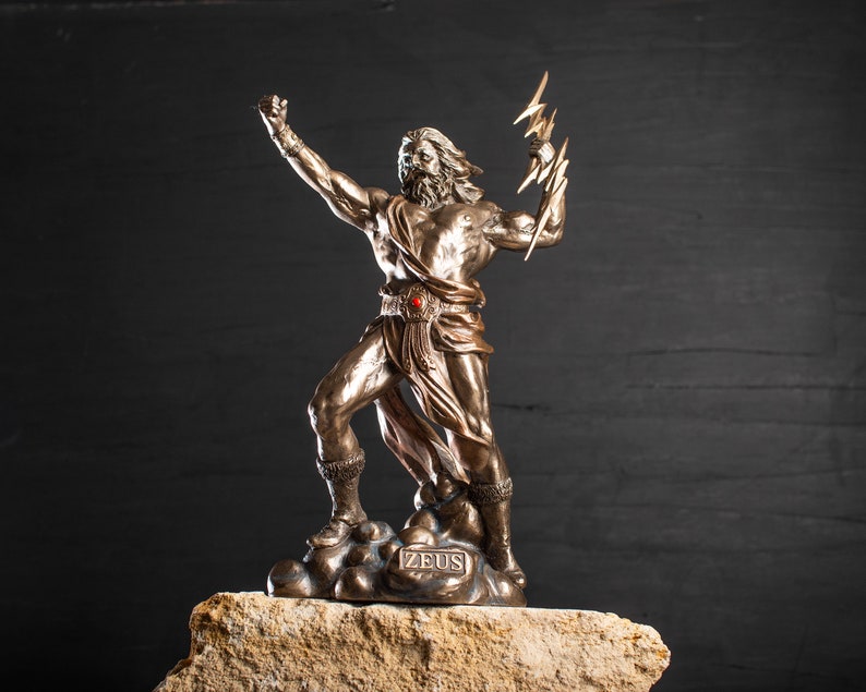 K&ouml;nnte beinhalten: Eine Bronzestatue von Zeus, dem griechischen Gott des Himmels und des Donners, der einen Blitz in seiner rechten Hand h&auml;lt. Die Statue steht auf einem Steinsockel mit der Aufschrift "ZEUS".