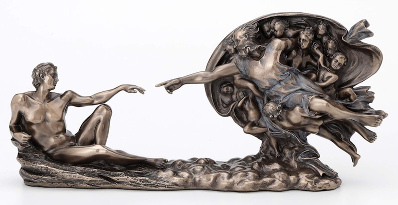May include: A bronze-toned sculpture depicting the Creation of Adam, featuring a reclining figure reaching out to touch the outstretched finger of a floating figure surrounded by a group of smaller figures within a circular, draped form.