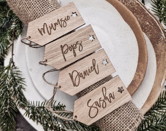May include: Four wooden place card holders with names "Mummy", "Pops", "Daniel", and "Sasha" engraved on them. Each card has a small star cutout.