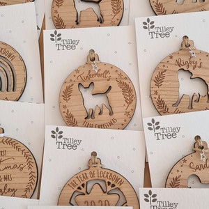 May include: A collection of personalized wooden Christmas ornaments featuring various dog breeds, names, and the year 2020. The ornaments are decorated with stars and leaves.