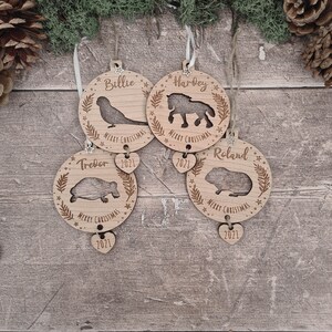 May include: Four wooden Christmas ornaments with personalized names, animal silhouettes, and the year 2021. The ornaments are Billie with a bird, Tredor with a turtle, Hardey with a horse, and Roland with a guinea pig.
