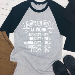 May include: A gray and black baseball tee shirt with the text "ALWAYS GIVE 100% AT WORK" and a list of days of the week with percentages next to them.