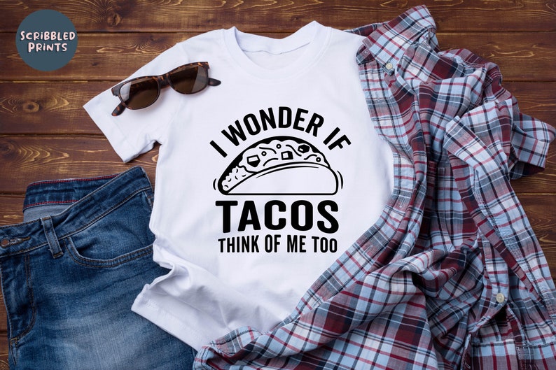 May include: White t-shirt with black text that reads "I wonder if tacos think of me too". The text is accompanied by a black and white illustration of a taco.
