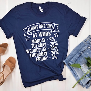 May include: A navy blue t-shirt with white text that reads "Always Give 100% At Work" and lists the days of the week with a percentage next to each day. The percentages decrease as the week goes on, with Monday at 9% and Friday at 3%.