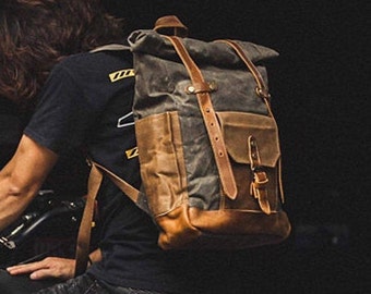 May include: A brown leather and canvas backpack with a roll-top closure and adjustable straps. The backpack has a large main compartment and a smaller front pocket.
