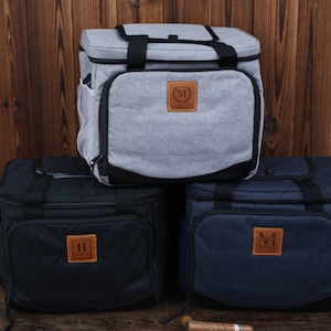 K&ouml;nnte beinhalten: Drei isolierte Lunch-Taschen mit personalisierten Leder-Patches. Die Taschen sind grau, schwarz und blau. Die Patches haben die Initialen "M", "H" und "M".