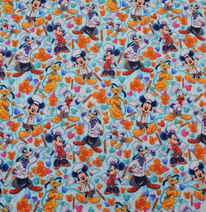 Puede incluir: Una tela azul con un patr&oacute;n repetido de Mickey Mouse, Donald Duck y Pluto. Mickey Mouse est&aacute; vestido de chef y sostiene una esp&aacute;tula. Donald Duck lleva un gorro de cocinero y sostiene un rodillo. Pluto lleva un gorro de cocinero y sostiene un batidor. El fondo es azul claro con un patr&oacute;n de orejas de Mickey Mouse, remolinos y palos.