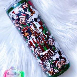 Pode incluir: Um copo verde e branco com um design de Natal com o Mickey Mouse e o texto "Feliz Natal".