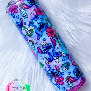 May include: A blue and pink stainless steel tumbler with a glitter rim. The tumbler features a repeating pattern of Stitch from Lilo & Stitch, flowers, and tropical leaves.