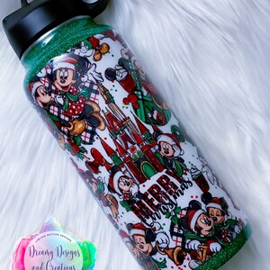 Pode incluir: Garrafa de &aacute;gua de a&ccedil;o inoxid&aacute;vel com glitter verde sobre um fundo branco com um design de Natal com os personagens Mickey Mouse e Minnie Mouse, as palavras "Feliz Natal" e o Castelo da Cinderela.