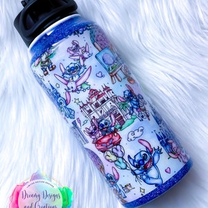 Op de afbeelding: Een blauwe en witte roestvrijstalen waterfles met een zwarte dop. De fles is versierd met een cartoonfiguur en verschillende kleurrijke ontwerpen. De fles heeft een glitterafwerking.