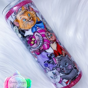 May include: A pink and white tumbler with a glitter rim features a colourful collage of cartoon cats from the Disney movie The Aristocats. The tumbler has the text "Dreamy Designs and Creations" on the side.