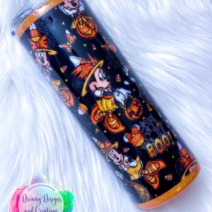 May include: A black and orange tumbler with a Halloween-themed design featuring Mickey Mouse dressed as a witch. The tumbler has a glitter finish and says "Boo!" on the side.