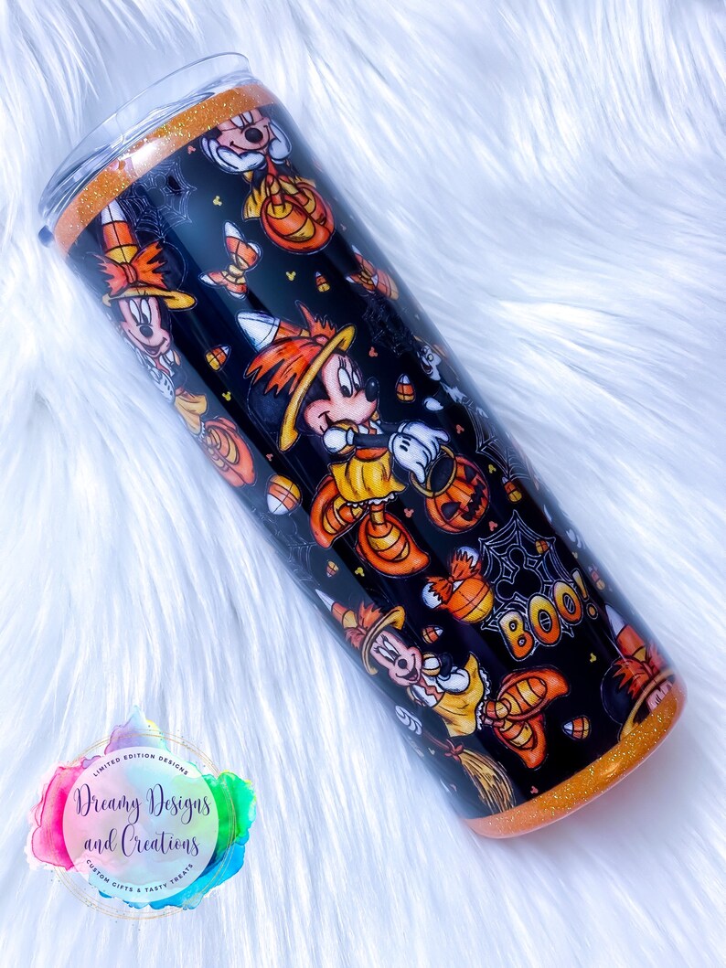 May include: A black and orange tumbler with a Halloween-themed design featuring Mickey Mouse dressed as a witch. The tumbler has a glitter finish and says "Boo!" on the side.