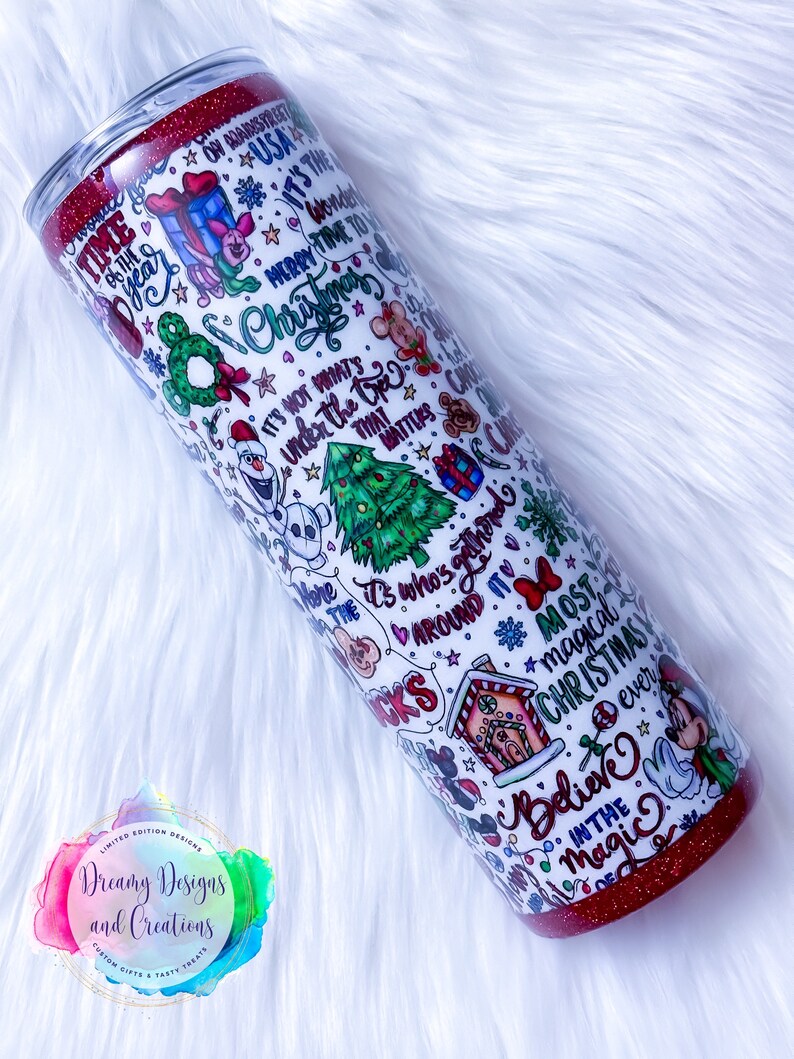 Pu&ograve; includere: Un bicchiere bianco con un coperchio rosso glitterato. Il bicchiere &egrave; ricoperto da un design a tema natalizio con personaggi dei cartoni animati, fiocchi di neve e il testo "&Egrave; il Natale pi&ugrave; magico di sempre. Credi nella magia."