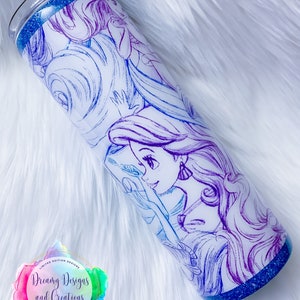 Puede incluir: Un vaso blanco con un borde de purpurina azul y un dibujo de contorno morado y azul de una princesa Disney con el pelo largo. El vaso tiene una pegatina con el texto "Dreamy Designs and Creations" en la parte inferior.