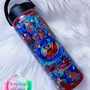 May include: A red glitter tumbler with a black lid and handle. The tumbler features a colorful design of Mickey Mouse and other Disney characters. The text "Dreamy Designs and Creations" is printed on the tumbler.