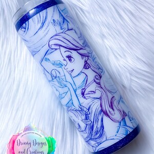 Puede incluir: Un vaso de acero inoxidable blanco con un borde de purpurina azul y un dibujo de l&iacute;nea azul y morado de una princesa con el pelo largo. El vaso tiene una pegatina con el texto "Dreamy Designs and Creations Custom Gifts & Tasty Treats".