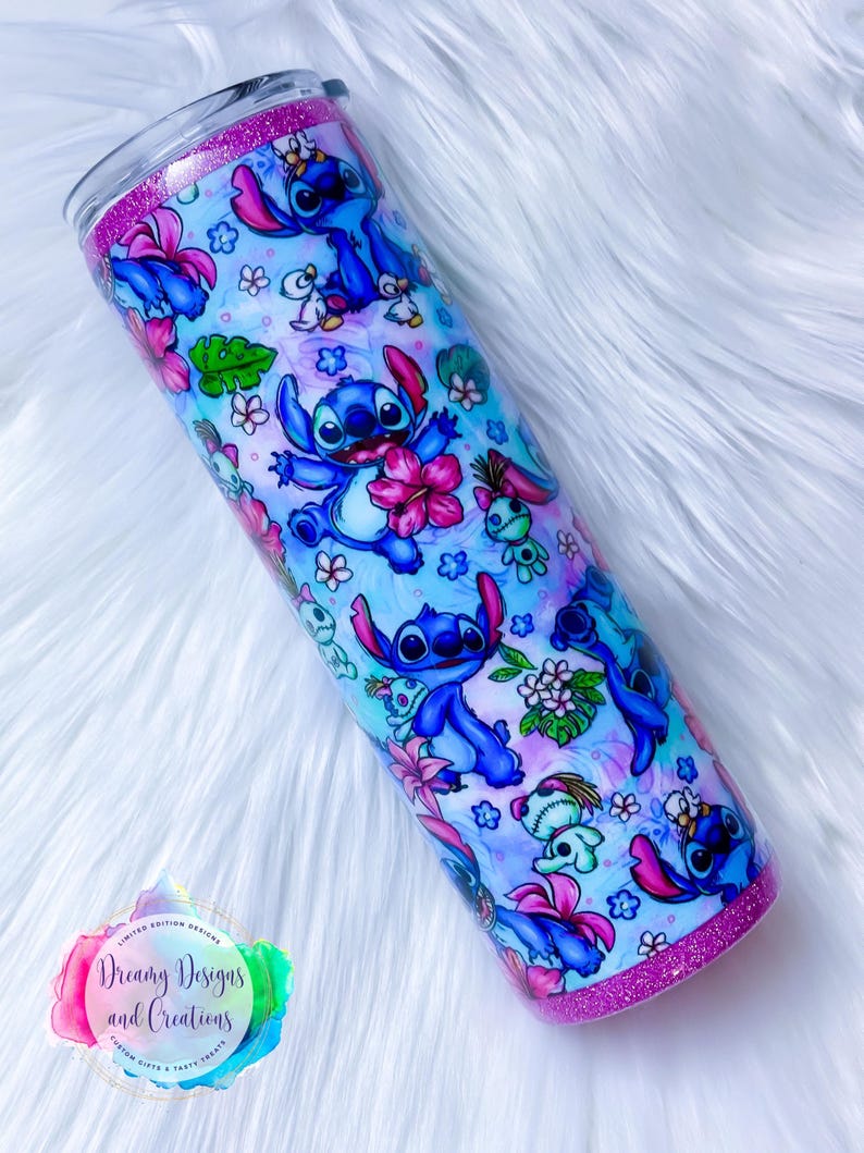 May include: A stainless steel tumbler with a pink glitter rim and a blue and white design featuring Stitch from Lilo & Stitch. The design includes Stitch in various poses, flowers, and other tropical elements. The tumbler is 20 ounces.