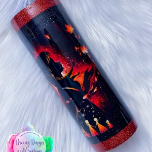 Op de afbeelding: Een zwarte en rode glitterbeker met een silhouet van een vrouw en twee kinderen voor een rode en oranje achtergrond. De beker heeft een rode glitterrand en -basis. De tekst "Dreamy Designs and Creations" staat op de beker.