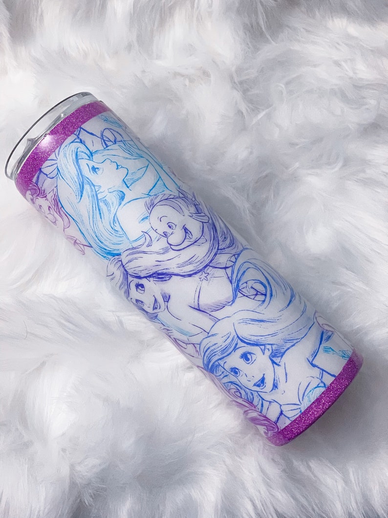 Puede incluir: Un vaso de acero inoxidable con un acabado de purpurina morado y un dise&ntilde;o blanco con los personajes de La Sirenita. El dise&ntilde;o incluye a Ariel, Sebasti&aacute;n y Flounder.