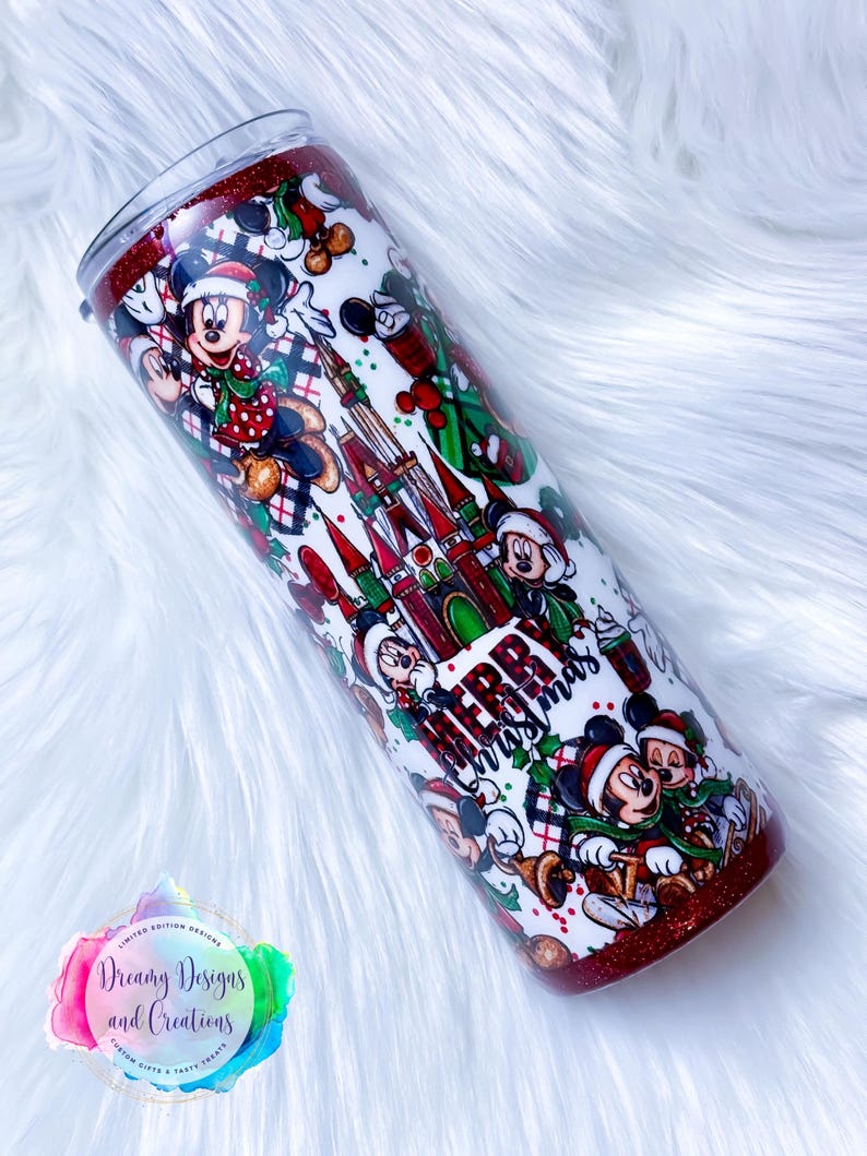 Pode incluir: Um copo vermelho e branco com tema natalino com Mickey Mouse e as palavras "Feliz Natal". O copo &eacute; coberto com um padr&atilde;o de personagens do Mickey Mouse, &aacute;rvores de Natal e o Castelo da Cinderela.