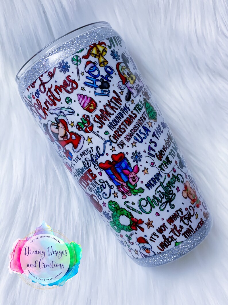 Pu&ograve; includere: Un bicchiere bianco con un bordo di glitter argentato presenta un design a tema natalizio con Topolino, Minnie Mouse e altri personaggi Disney. Il design include il testo "&Egrave; il periodo pi&ugrave; bello dell'anno", "Ho Ho Ho", "Buon Natale" e "Non &egrave; quello che c'&egrave; sotto l'albero che conta".