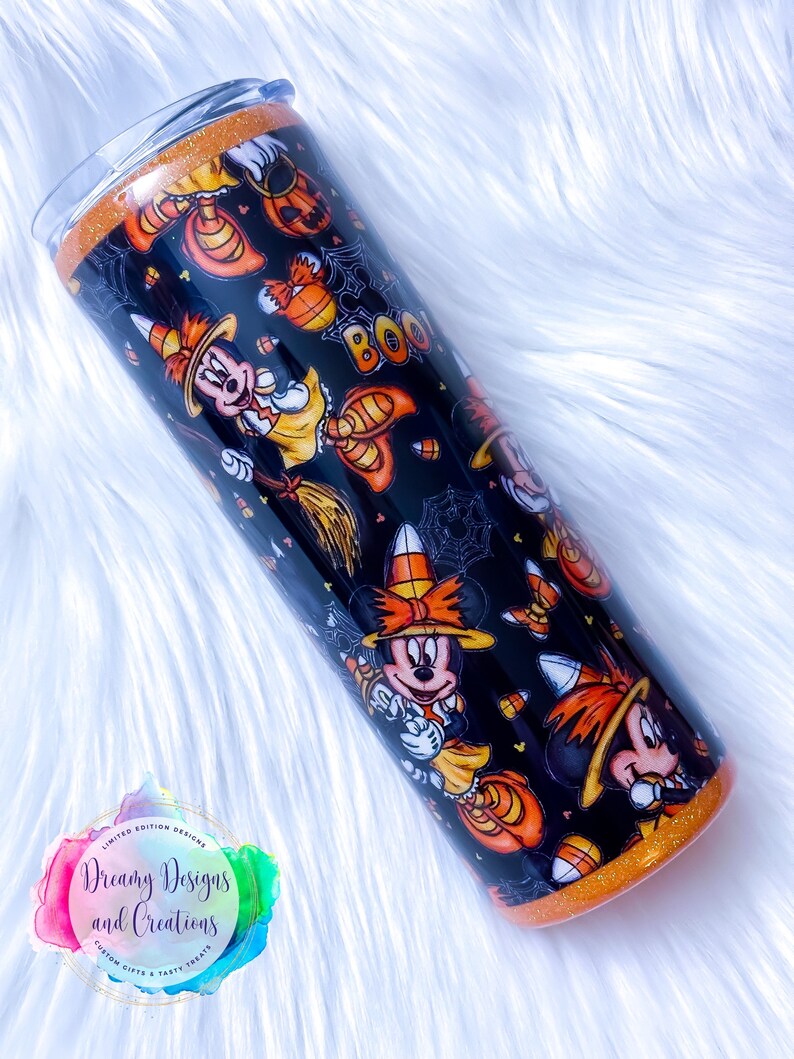 May include: A black and orange tumbler with a Halloween-themed design featuring Mickey Mouse dressed as a witch. The tumbler has a glitter finish and says "Boo!" on the side.