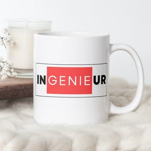Peut inclure: Une tasse en céramique blanche avec un contour noir et un fond rouge sur lequel est inscrit "INGENIEUR" en lettres noires.